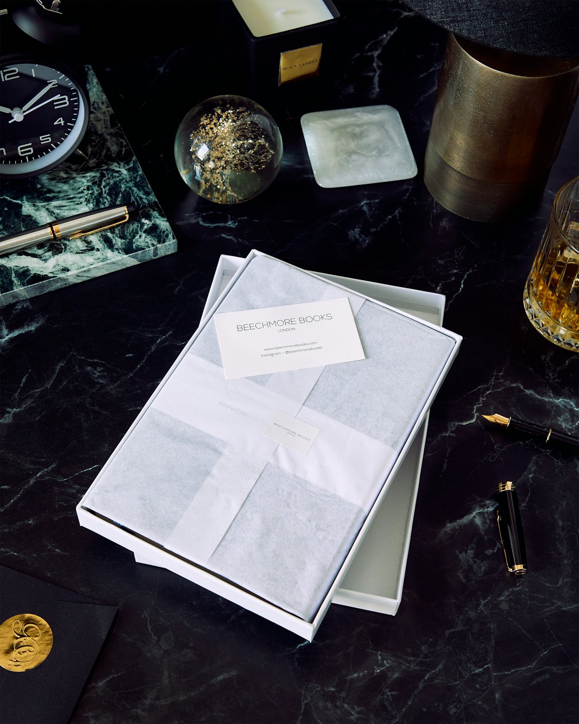 An open gift box and desk accessories sit on a marble desk.