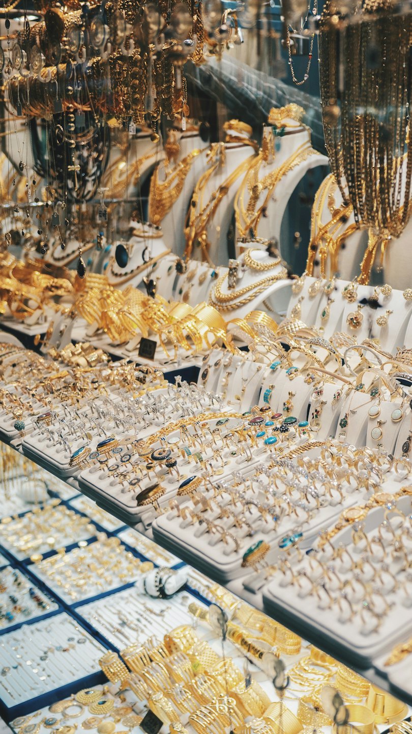 Gold and silver necklaces, rings, and bracelets displayed indoors.