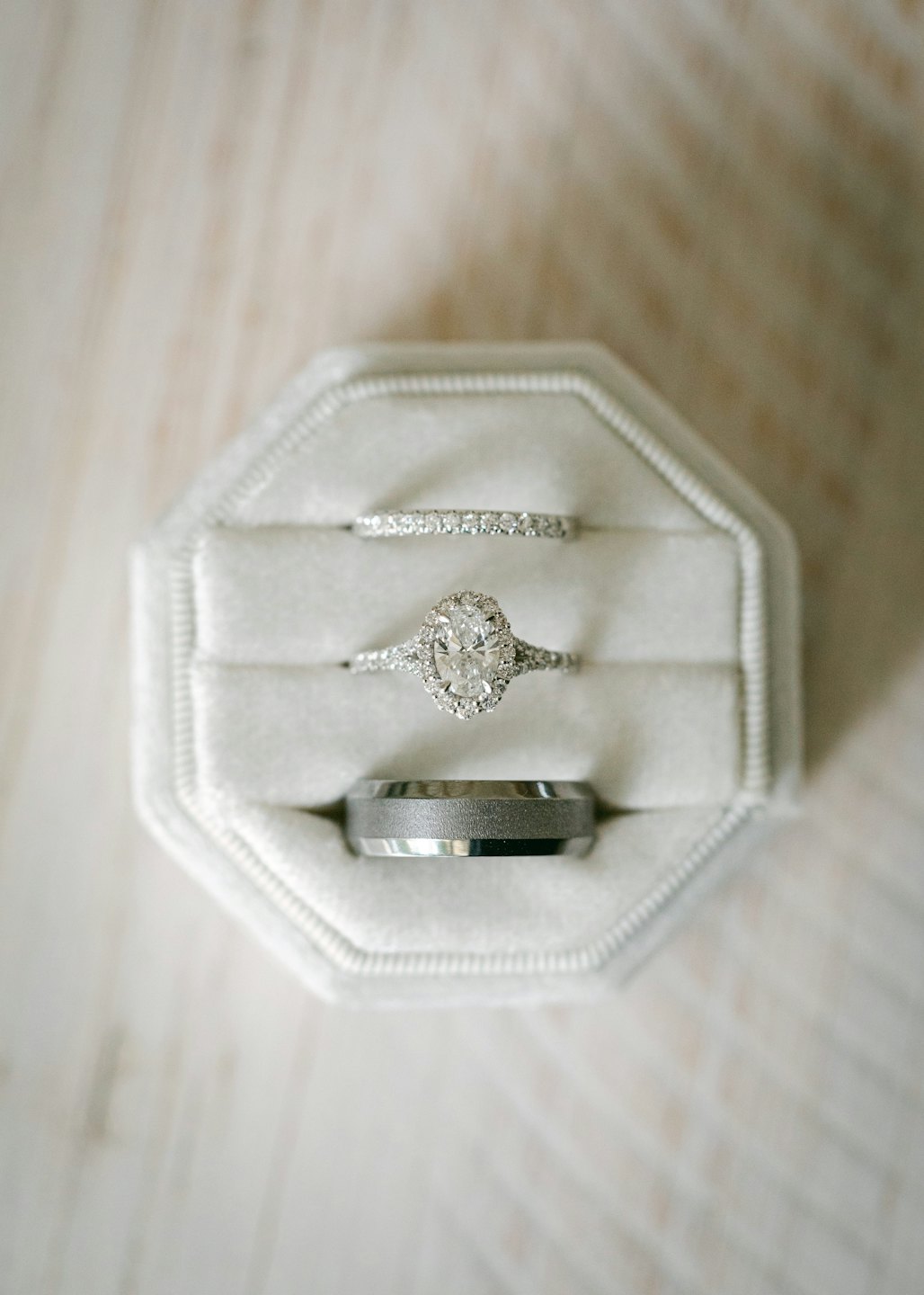 Three wedding rings rest inside a grey velvet octagonal box.