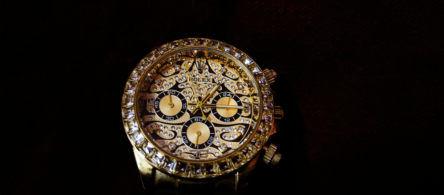 A gold diamond-encrusted luxury watch with a black dial.